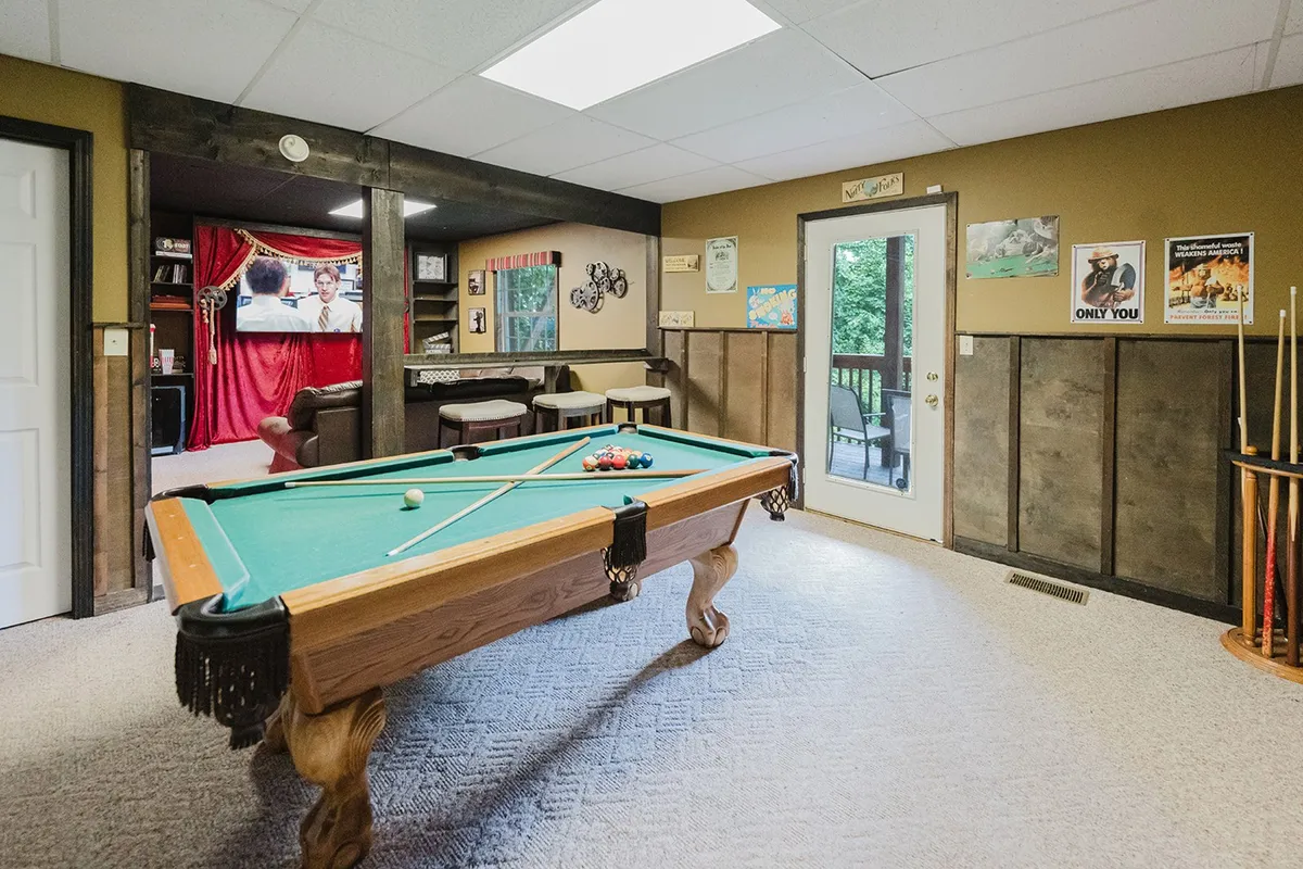 This image centers on a regulation pool table in a vibrant recreation room. A door leads outside, and decorative wall art adds personality, capturing the lively, social atmosphere of the space. The setup invites friendly competition and offers direct access to fresh air between rounds.