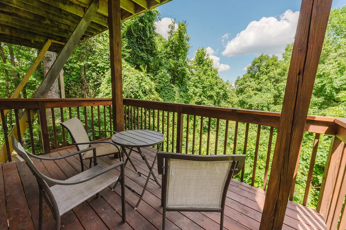 A peaceful wooden deck furnished with two comfortable chairs and a small table, surrounded by lush greenery. The deck offers a tranquil spot for relaxation and direct connection with nature, inviting guests to enjoy quiet moments, wildlife watching, or a morning coffee outdoors.