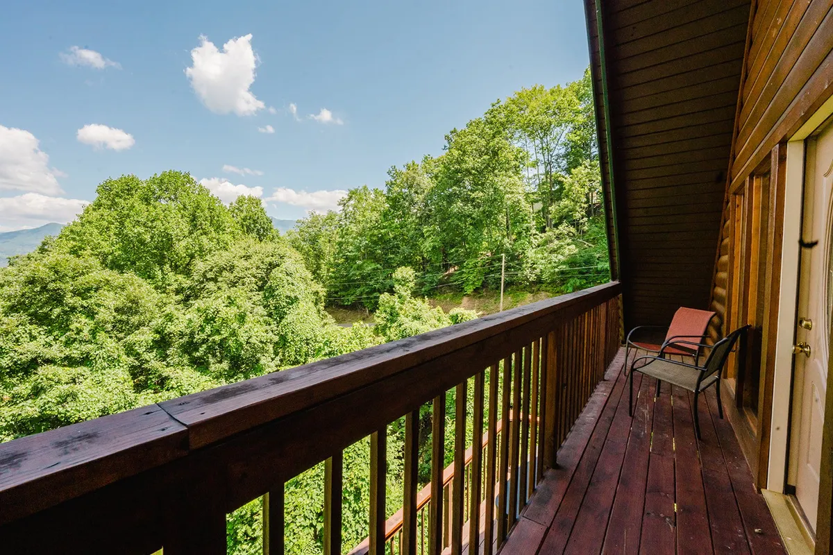 A quiet corner of a wooden deck shows a lone chair facing out toward tree-filled surroundings. The mood is peaceful and contemplative, ideal for wildlife watching, sunrise coffee, or stargazing under the night sky.