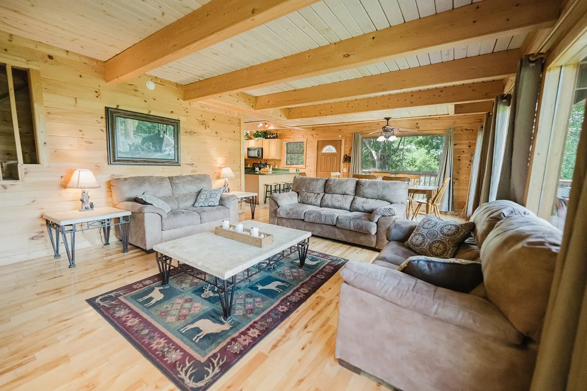 A cozy living area featuring comfortable sofas, a coffee table, a playful rug with animal motifs, and large windows providing ample natural light. The room invites relaxation, reading, or family game nights, embodying warmth and togetherness.